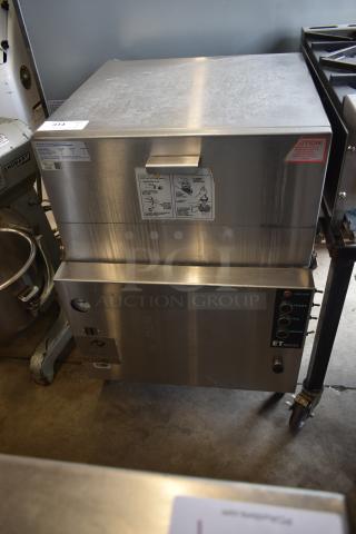 Stainless steel commercial steamer with control panel. ET Series; buttons for start, fill, drain. Visible instructions and caution label.