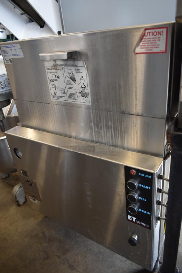 Stainless steel commercial dishwasher, ET Series, with control panel and maintenance instructions visible. Signs of light wear.