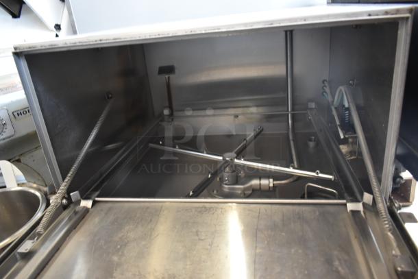 Commercial stainless steel dishwasher interior with rotating spray arms, springs, and pipes; clean and well-maintained.