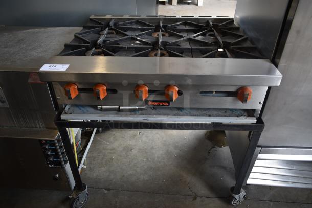 Commercial countertop gas stove with six burners and orange control knobs. Sierra brand. Item tag "315" visible.