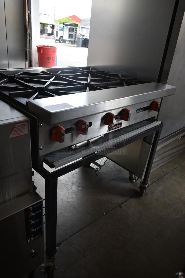 Commercial gas range with six burners, stainless steel, red control knobs, used condition, minor wear. Marked "Vulcan."