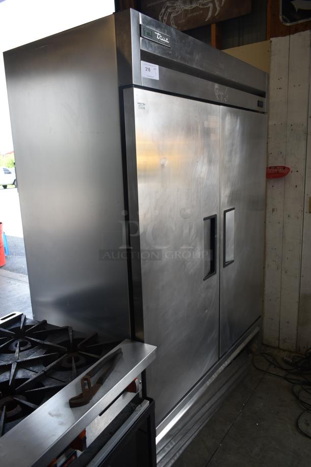 True double-door commercial refrigerator in stainless steel. Good condition, visible label with model number and auction tag.
