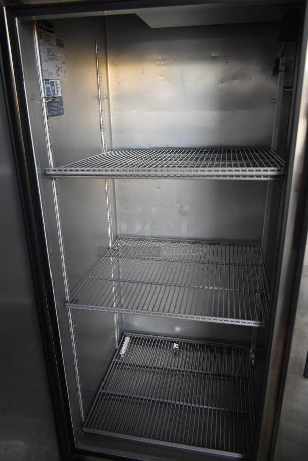 Commercial stainless steel refrigerator with three adjustable wire shelves. Tag indicates Energy Star rating.