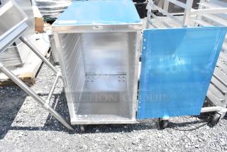 Stainless steel rolling cart with blue protective film, open door, interior shelves, and caster wheels; in excellent condition.