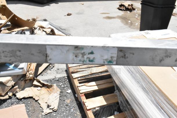 Metal beam with worn and faded label on industrial pallet. Appears used, in fair condition, label details illegible.