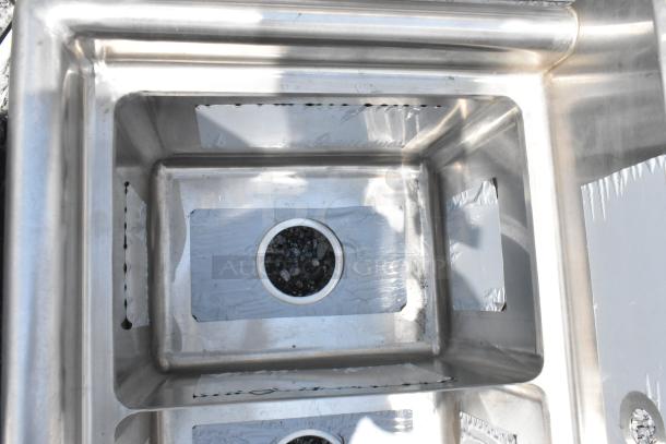 Stainless steel deep sink with dual basins, circular drain openings, and protective film. Appears unused, no visible markings.