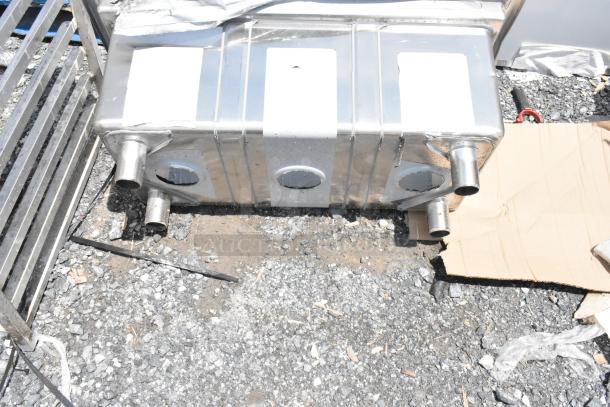 Stainless steel exhaust muffler with multiple inlets and outlets, lightly scratched, no visible brand or model.