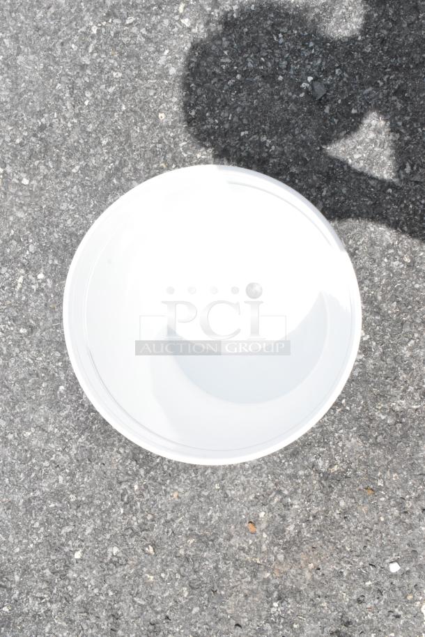 White ceramic bowl on gray pavement, in excellent condition, glossy finish, simple design, no visible markings.