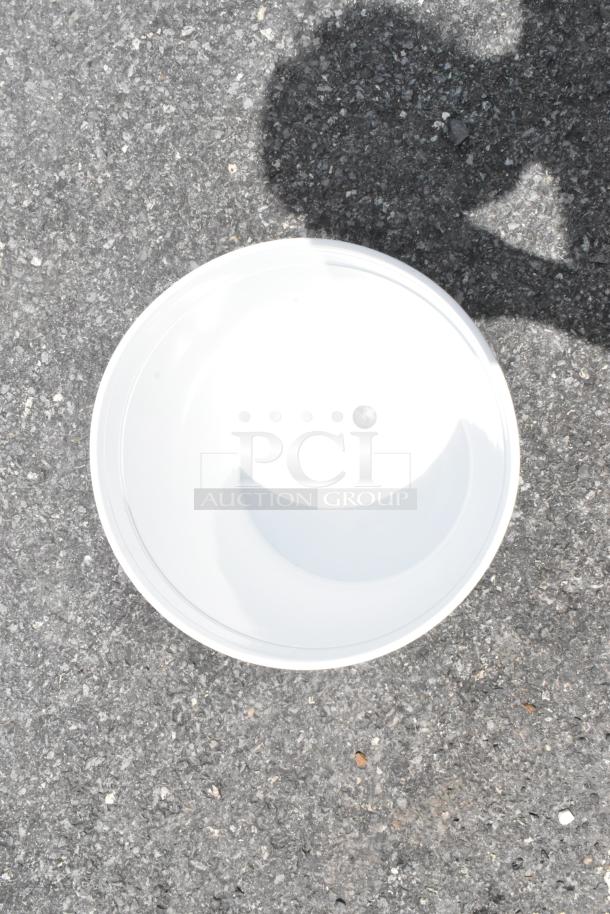 White ceramic bowl with a glossy finish, placed on asphalt. No visible markings or labels.