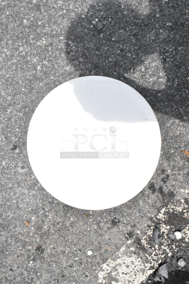 White round plate on asphalt surface, showing no visible markings or tags. Suitable for auctions as a minimalistic decor piece.