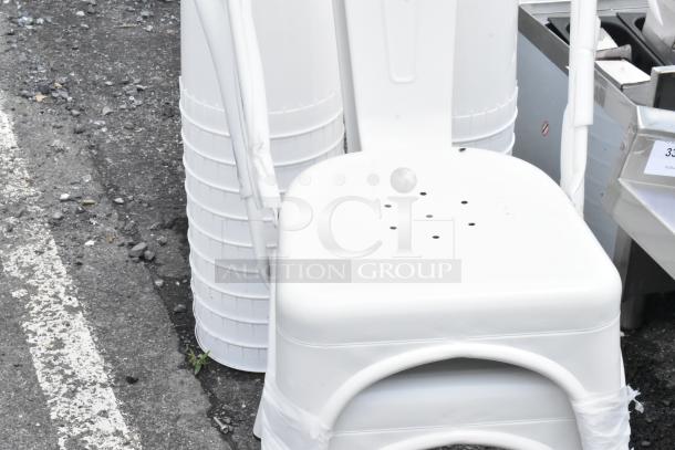 White metal chair with perforated seat, appears new with plastic wrapping, ideal for outdoor use.