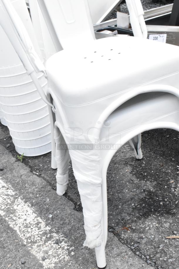 White metal stool with protective wrap on legs, showing minor wear. Perforated seat for ventilation.
