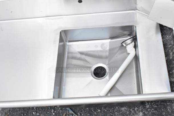 Stainless steel sink with integrated drain, unused condition, includes attached drain pipe.