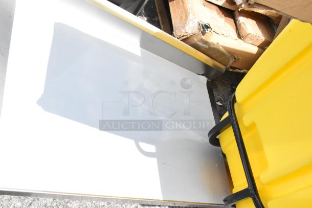White metal sheet with slight damage, stacked with yellow plastic storage bin and cardboard boxes. Used condition.