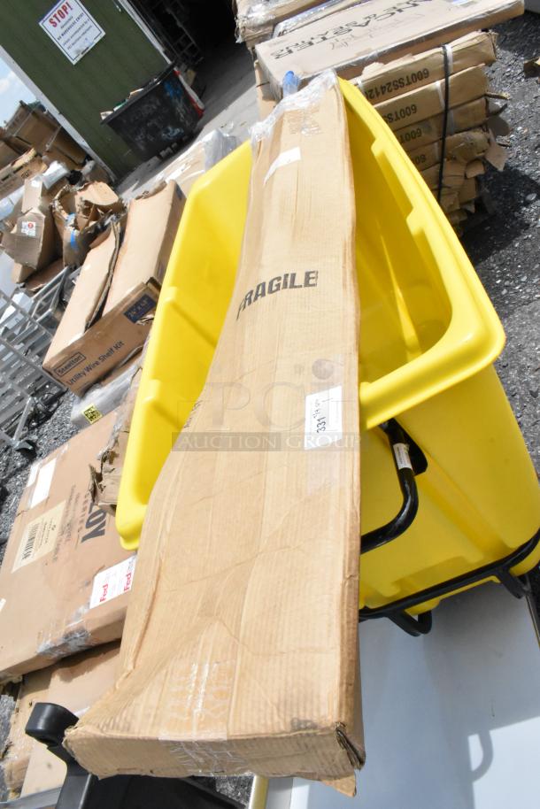 Long cardboard box labeled "FRAGILE" on yellow cart, outdoors. Box shows wear, condition unknown. Tag with numbers visible.