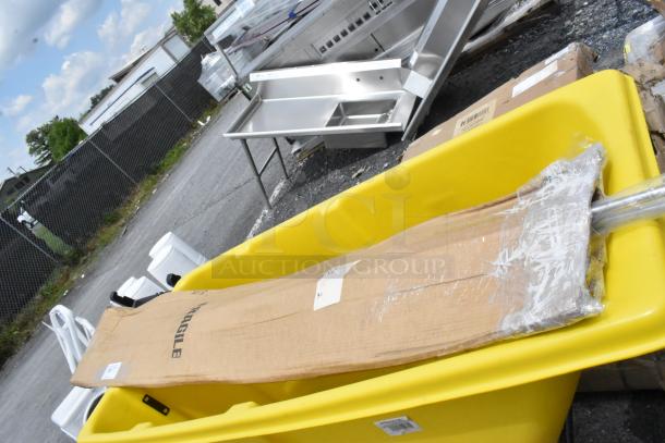 Large yellow utility cart containing a cardboard box labeled "FRAGILE" with wrapped metal parts inside. Labels visible on the cart.