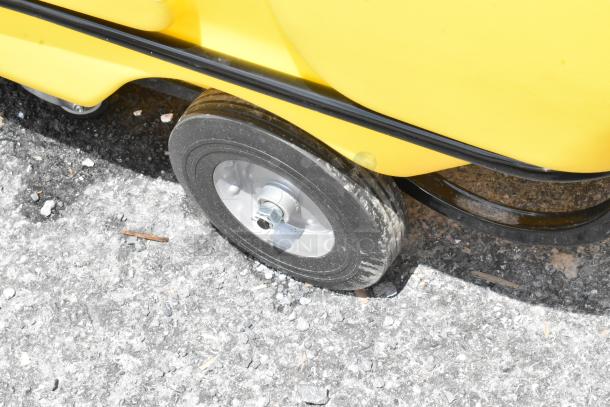 Yellow wheeled cart on textured ground; features black rubber tire, metal hub, and plastic body in good condition.