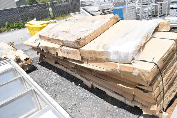 Pallet of stacked, unopened cardboard boxes in fair condition with visible creases, located outdoors.