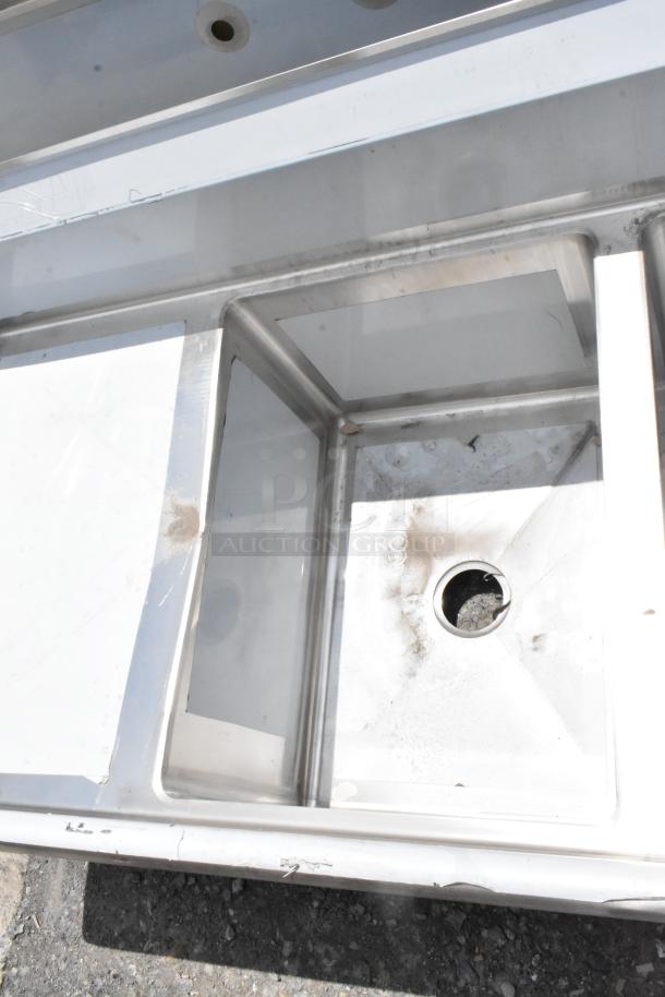 Stainless steel commercial sink with visible wear and a central drain hole. Shows signs of dirt and residue buildup.