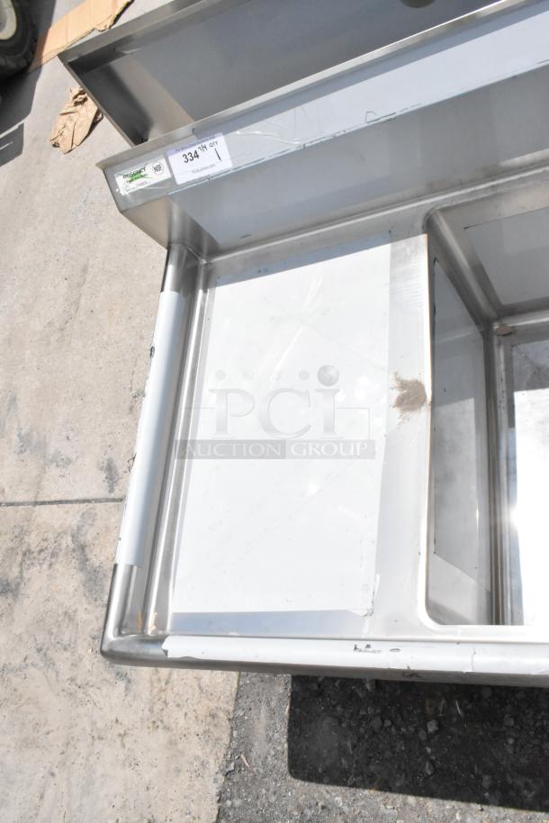 Stainless steel sink basin with integrated prep area, showing light wear and minor denting. Tag indicates model 334.