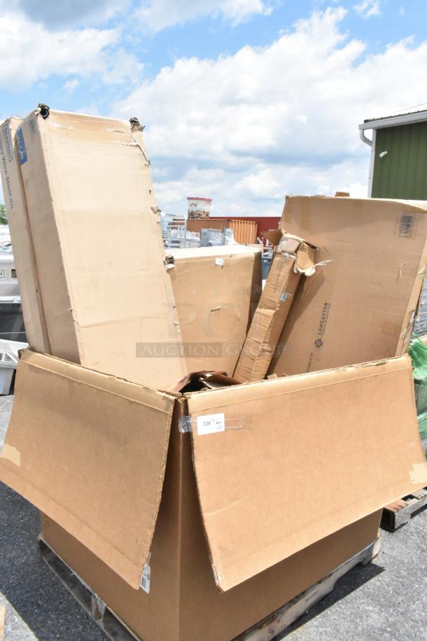 Large open cardboard box containing various smaller boxes, some labeled "Lancaster." Boxes show wear and tear, on a pallet outdoors.