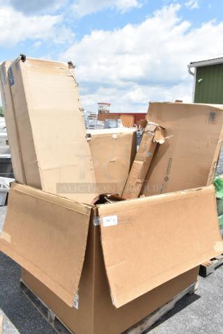 Large open cardboard box containing various smaller boxes, some labeled "Lancaster." Boxes show wear and tear, on a pallet outdoors.