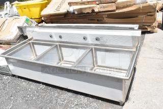 Stainless steel three-bay commercial sink in used condition, with mounting holes and a sturdy base.