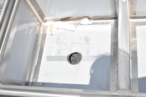 Stainless steel sink basin with drain hole, visible residue and wear, suitable for commercial-kitchen use.