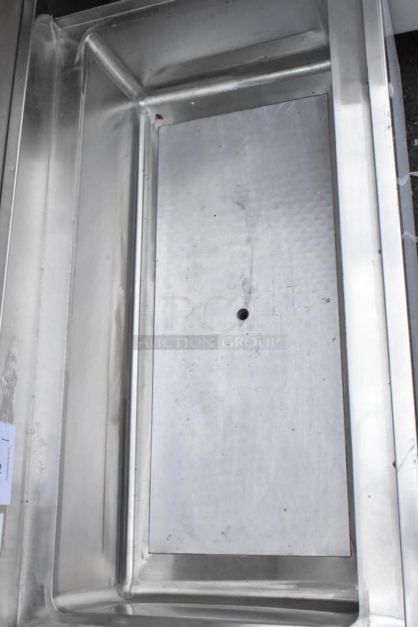 Stainless steel rectangular tray with a drain hole, polished finish, light wear, auction tag visible.