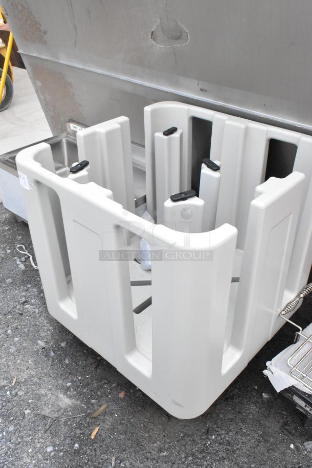 Large gray plastic equipment holder with multiple slots, in good condition. Auction label visible on the side.