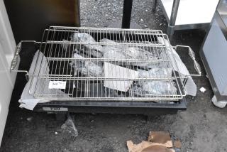 Stainless steel grill rack with handles, resting on a wheeled base; numbered tag "342" attached. Good condition.