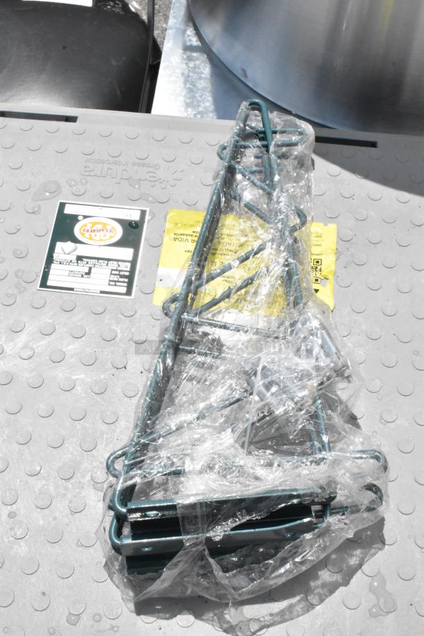 Green metal frame wrapped in plastic, on a textured surface. Labels indicate item weight and shipping details.