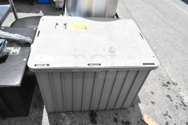 Large gray plastic storage container with textured lid and visible stickers. Condition shows outdoor usage.