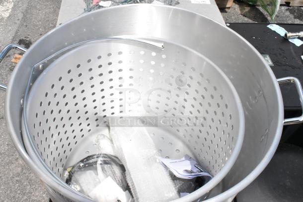 Large stainless steel stockpot with perforated insert and handles, in good condition. Includes packaging material and documents inside.