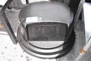 Black outdoor trash can with a domed lid, visible scuff marks, and a label numbered "349". Features swing door and sturdy base.
