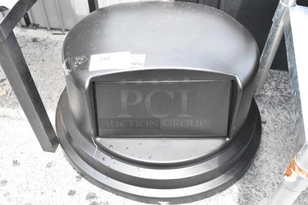 Black commercial trash can with dome lid, labeled "349". Used condition with scuffs, suitable for outdoor use.