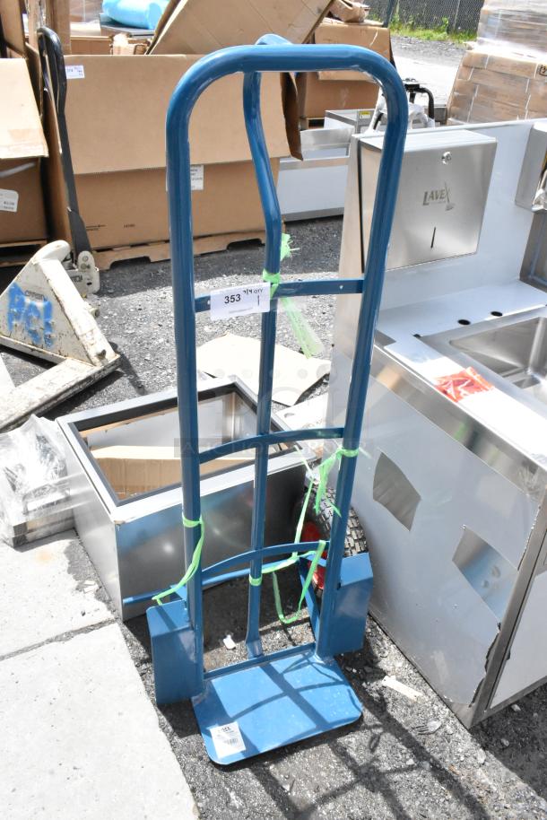 Blue hand truck with solid wheels, visible wear, and load capacity label "353." Tied with green straps.