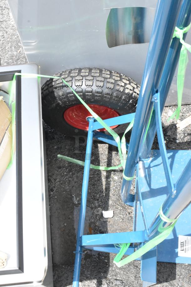 Blue hand truck with sturdy frame and large, treaded wheels. Lightly used condition with green straps attached.