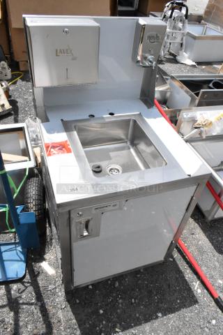 Stainless steel commercial hand sink with "Lavex" and "Novo" dispensers, labeled "Regency NSF," showing minor wear.