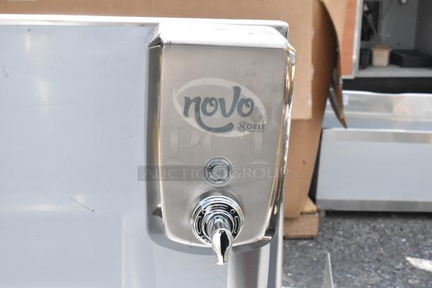 Stainless steel Novo Noble soap dispenser, excellent condition, wall-mounted, with push button and nozzle for dispensing.