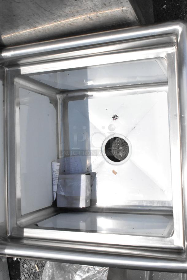 Stainless steel square sink with drain hole, clean condition, includes papers and plastic-wrapped items inside.