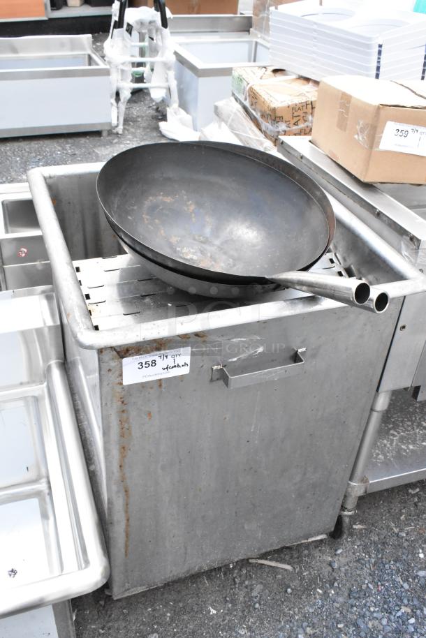 Large steel wok with twin handles resting on a stainless steel industrial sink. Visible tag reads "358" and "w/ contents." Slight rust visible.