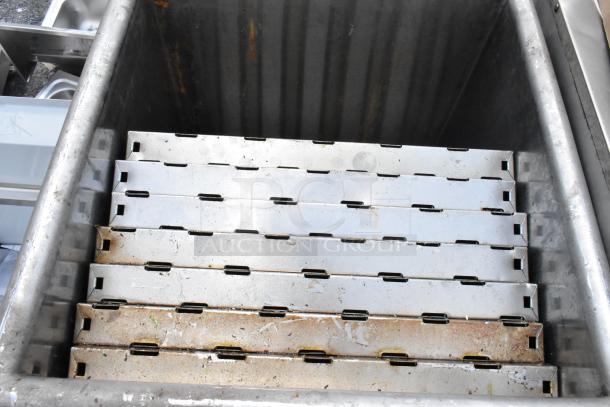 Metal industrial storage bin with six stackable trays, showing signs of rust and wear. Sturdy construction.