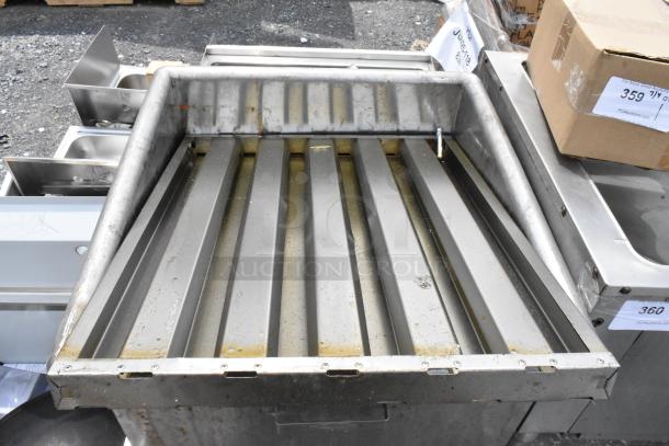Stainless steel commercial griddle tray, showing signs of wear, with visible grease stains and corrugated grooves.