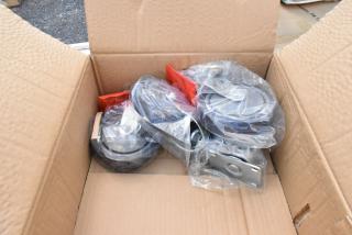 Box of new caster wheels, sealed in plastic, various sizes, metal base plates. Tags indicating model numbers visible.