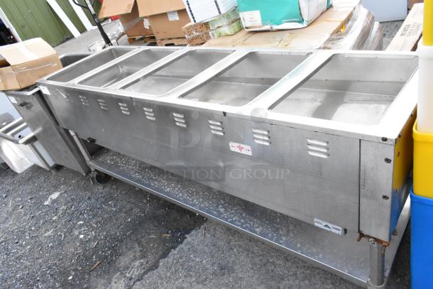 Stainless steel commercial buffet server with five food wells, on casters. Light wear. Labels with brand and instructions.