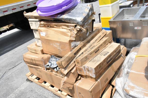 Stack of cardboard boxes labeled "Table Base Column & Rod," some damaged, on a wooden pallet with other items.