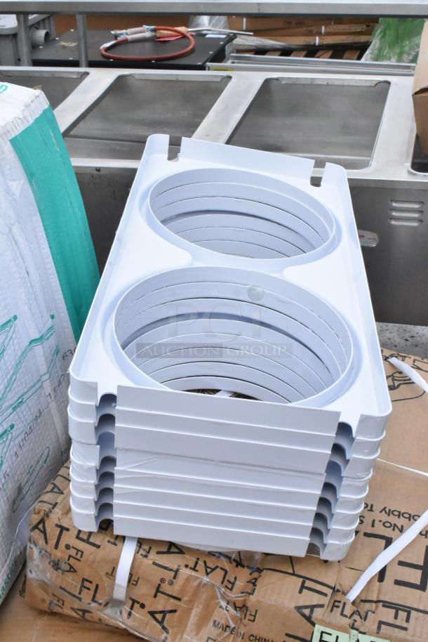 Stack of white plastic ring molds, new condition, for kitchen use, placed on cardboard with "FLAT" markings.