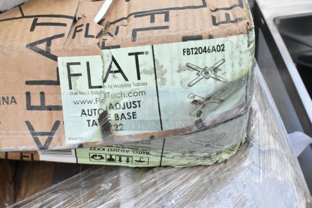 FLAT auto-adjust table base model FBT2046A02 packaging, visible wear and tear, partially wrapped in plastic.