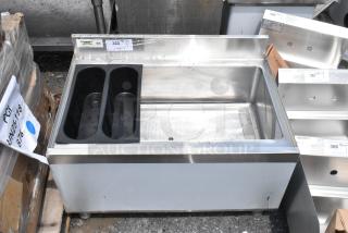 Stainless steel ice bin, dual black plastic bottle holders, used condition, labeled "Regency" and "NSF" on tag.